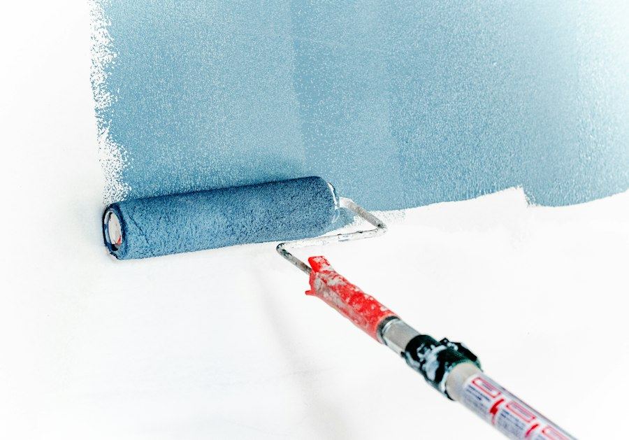 Paint roller applying blue wall paint